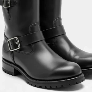 A close-up shot of a classic pair of black leather women's motorcycle boots with a simple, timeless design and thick, durable sole.