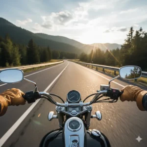 A first-person view of a motorcyclist wearing leather motorcycle mittens while riding on a scenic highway.