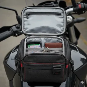 Overhead view showing the internal compartments of a small motorcycle tank bag holding a phone, keys, and wallet.