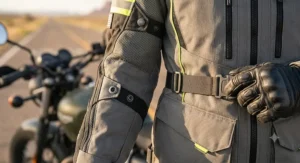 Close-up on the adjustable waist straps and arm snaps of a textile touring motorcycle jacket for a custom fit.