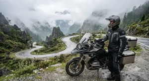 An adventure rider standing next to their motorcycle in a foggy mountain landscape wearing a durabl