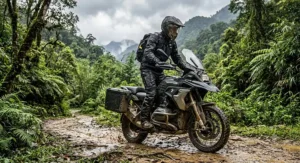 Dual-sport motorcycle rider wearing rugged men's riding overpants for rain protection on a wet adventure trail.