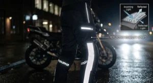 Illustration highlighting high-visibility reflective strips on waterproof motorcycle textile pants for night riding.