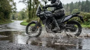 Close-up of affordable touring boots splashing through a shallow puddle on a country highway.