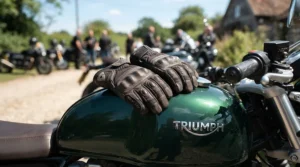 Lightweight breathable mesh gauntlet gloves for adventure riding placed on a motorcycle fuel tank in summer.