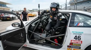 Driver stepping into a race car while wearing flexible budget racing boots for amateur racers