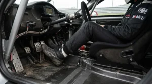Close-up of budget racing boots for amateur racers resting on vehicle pedals during a track session
