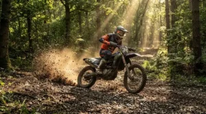Off-road gauntlet gloves for adventure riding in action as a dirt bike kicks up gravel on a trail.
