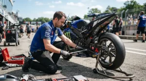 Mechanic inspecting sport riding boots for hot weather track days beside a sportbike on rear stands