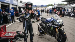 Rider checking gear and sport riding boots for hot weather track days inside a shaded paddock garage