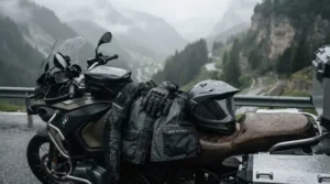 Waterproof gauntlet gloves for adventure riding resting on a motorcycle seat during a rainy mountain touring trip.