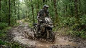 Rider putting waterproof touring boots for rain riding through muddy puddles on a dirt trail
