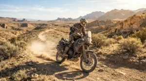 A rider wearing affordable adventure riding boots navigating a rocky dirt trail in the desert.