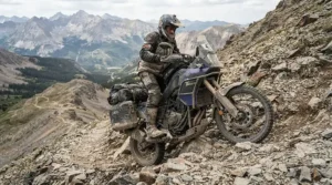 A dual sport rider planting their budget dual sport motorcycle boots onto rocks during a tough uphill climb.
