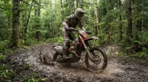 Rider wearing off-road motorcycle boots for trail riding navigating through thick, wet woodland mud.